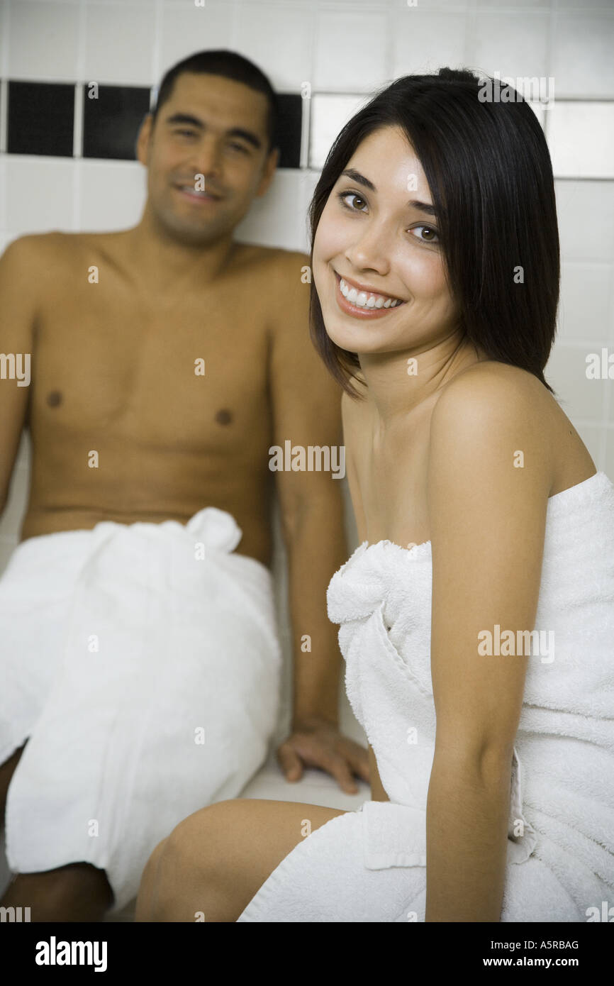 Man and woman in steam bath with towels smiling - Foto de stock