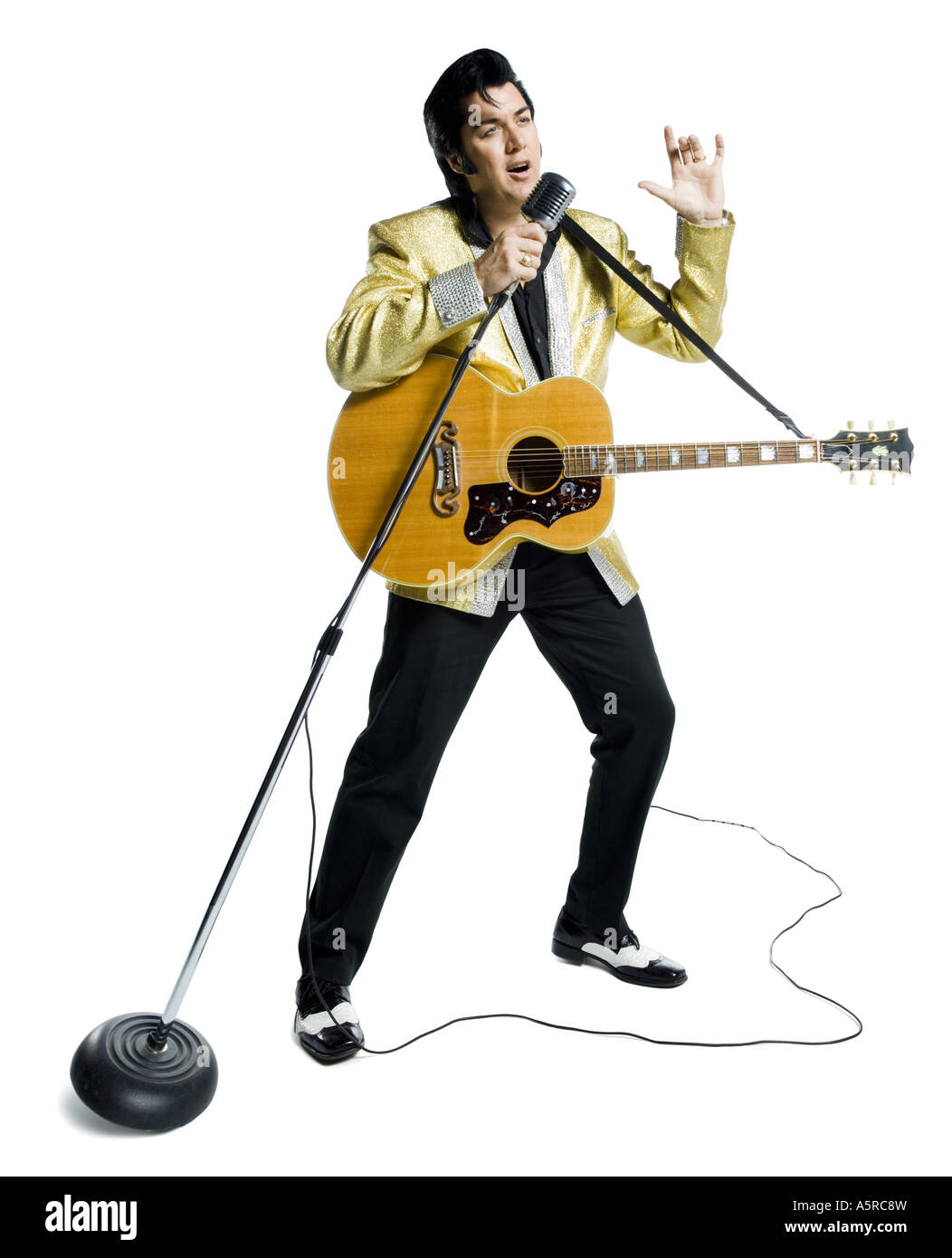 An Elvis impersonator singing into a microphone Stock Photo