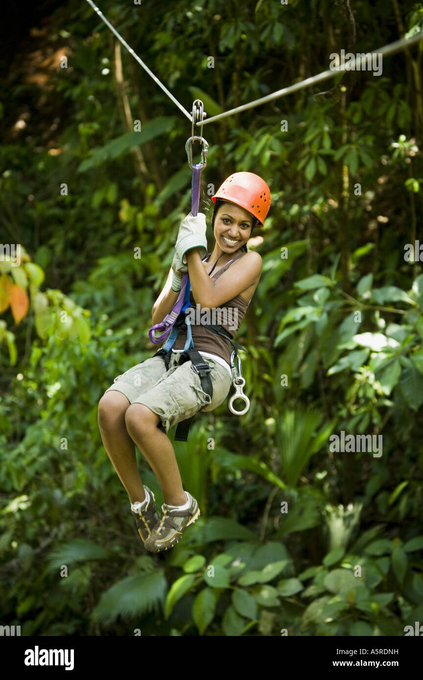 Young woman hanging from a zip line and smiling Stock Photo