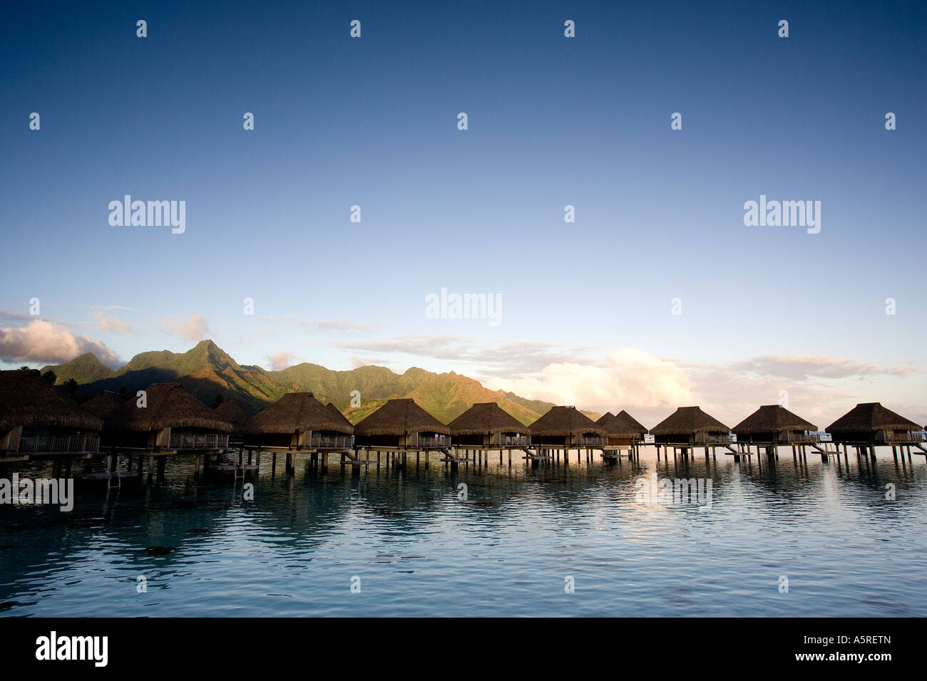 ISOLATION OF A FARAWAY ISLAND IS CAPTURED BY A SCENIC OF OVERWATER BUNGALOWS IN FRENCH POLYNESIA Stock Photo