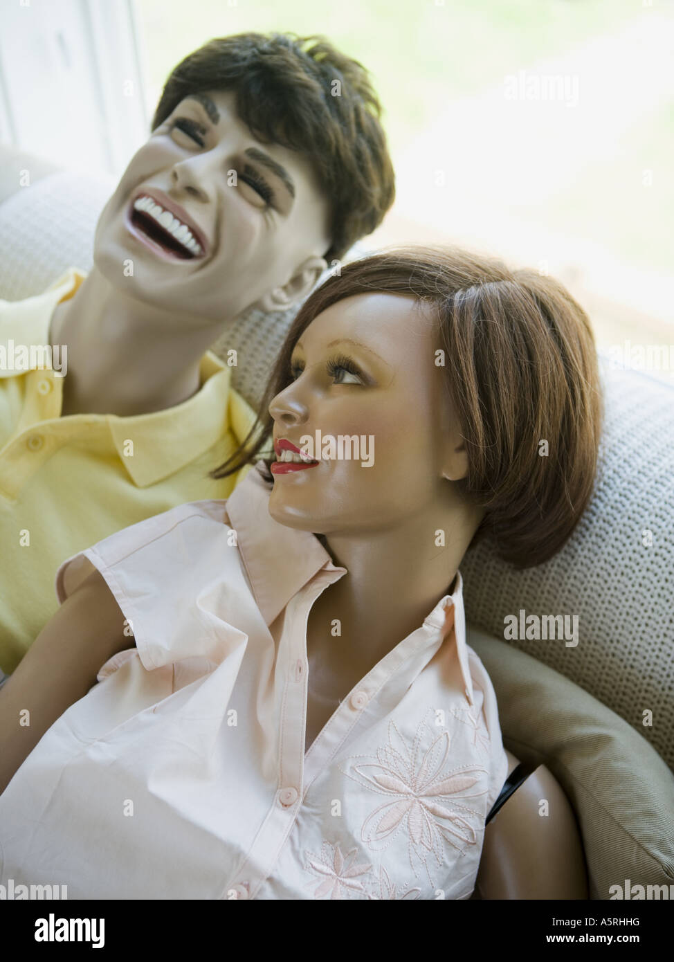 Close up of a male mannequin and a female mannequin laughing on a couch