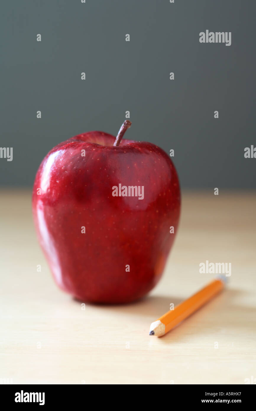 Red apple and pencil on school desk. Stock Photo