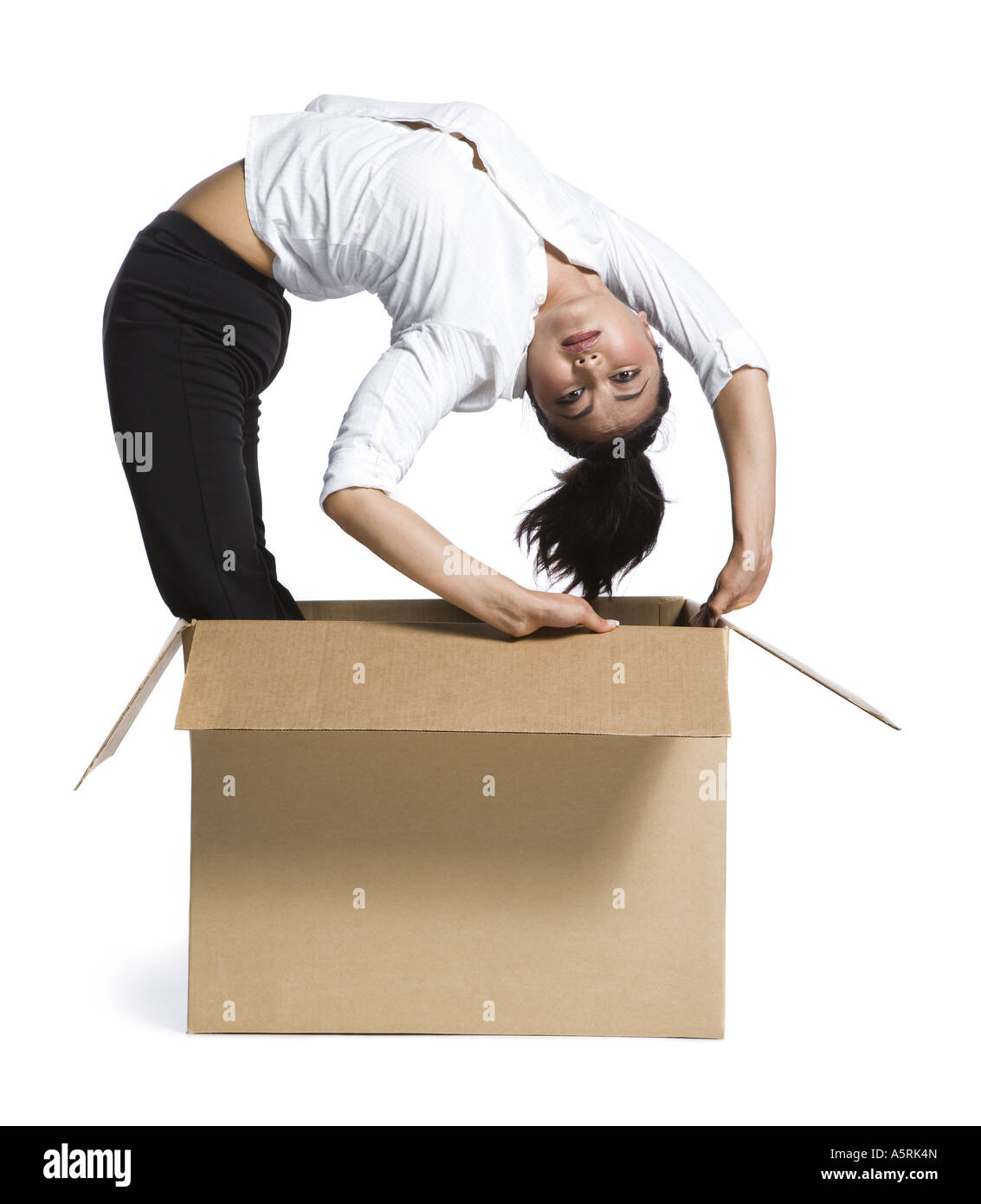 Female contortionist businesswoman inside cardboard box Stock Photo