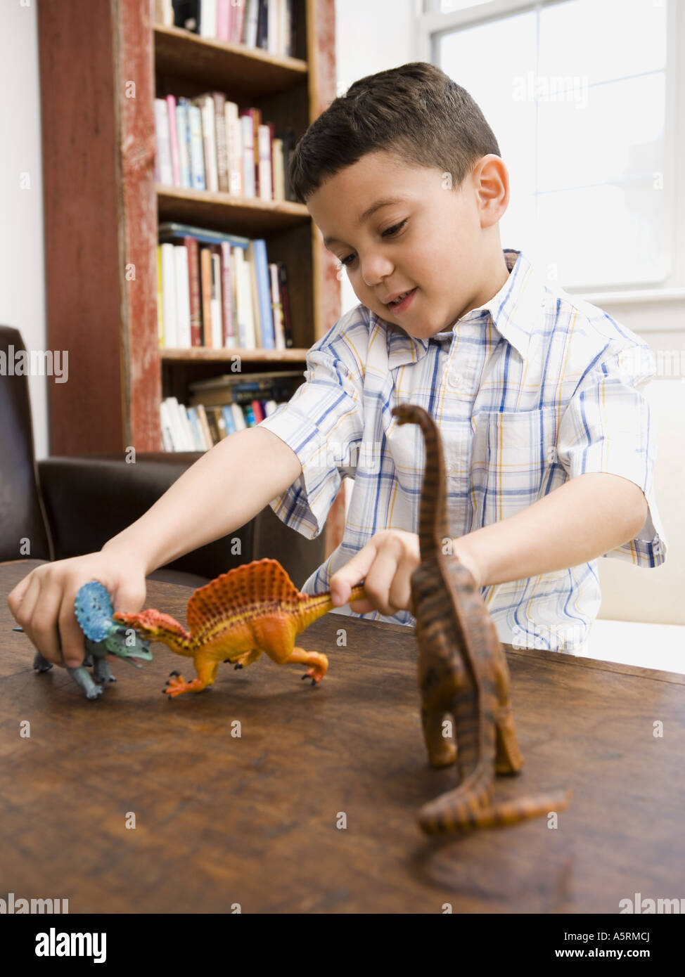 Young boy playing with toy dinosaur figures Stock Photo