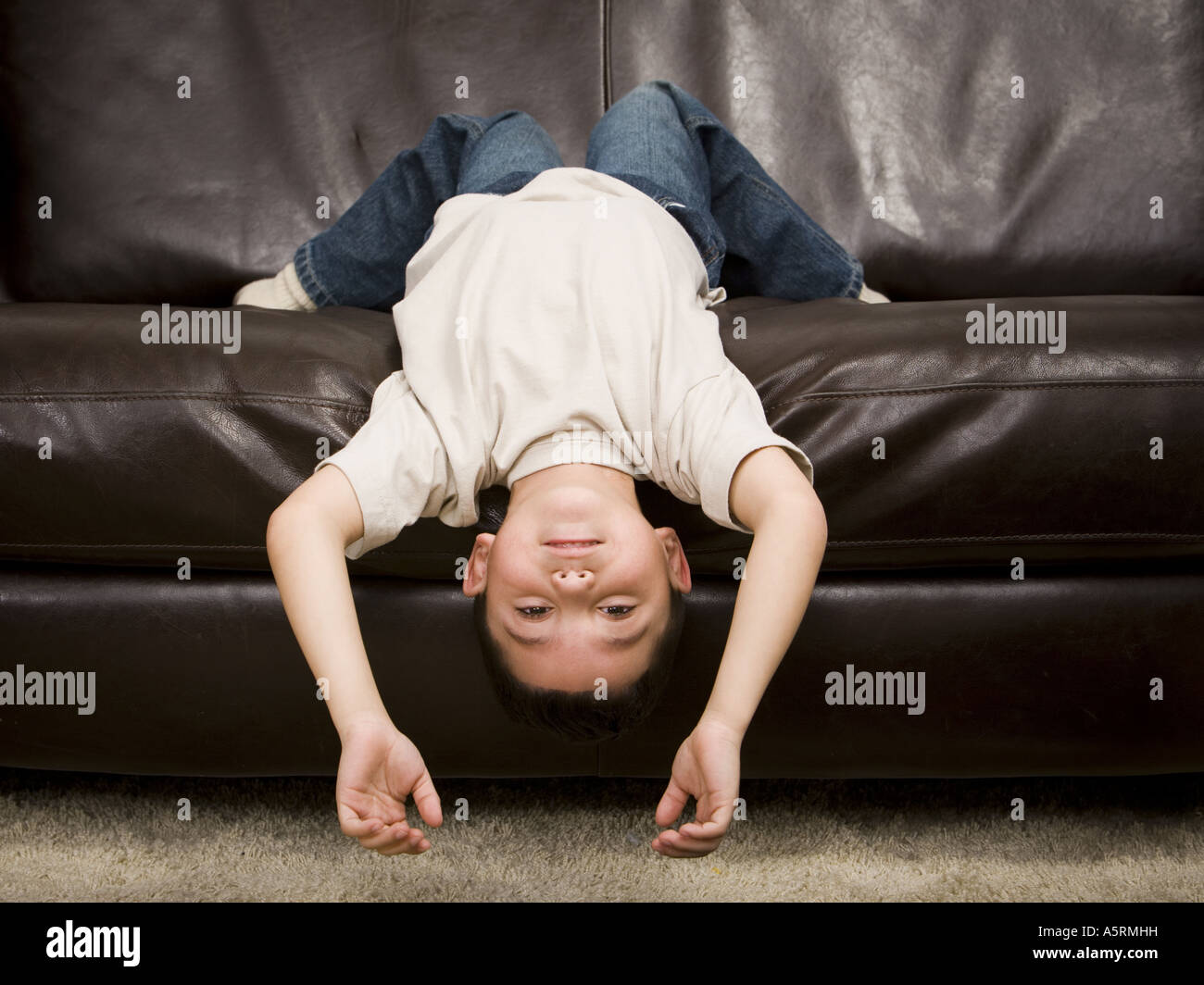 Young boy lying upside down on a leather sofa Stock Photo Alamy