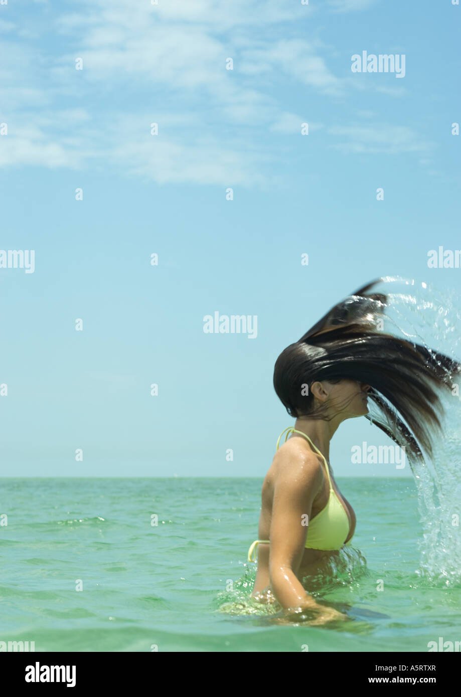 Woman standing in sea, flipping wet hair Stock Photo