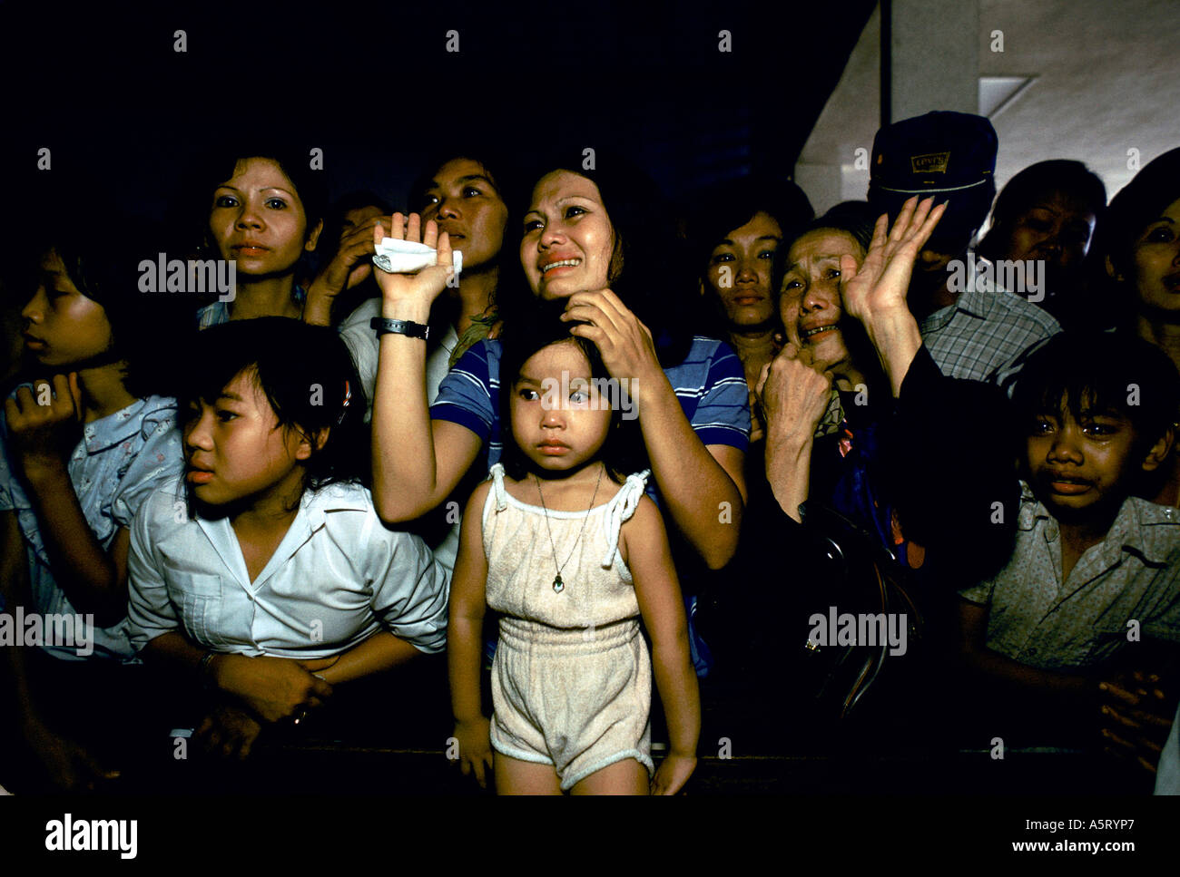 VIETNAM,  A WOMAN AND OLD LADY WAVING GOODBYE WHILE THE OTHERS LOOK ON WITH SADNESSAS FAMILIES GET SPLIT UP, SAIGON INT. AIRPO Stock Photo