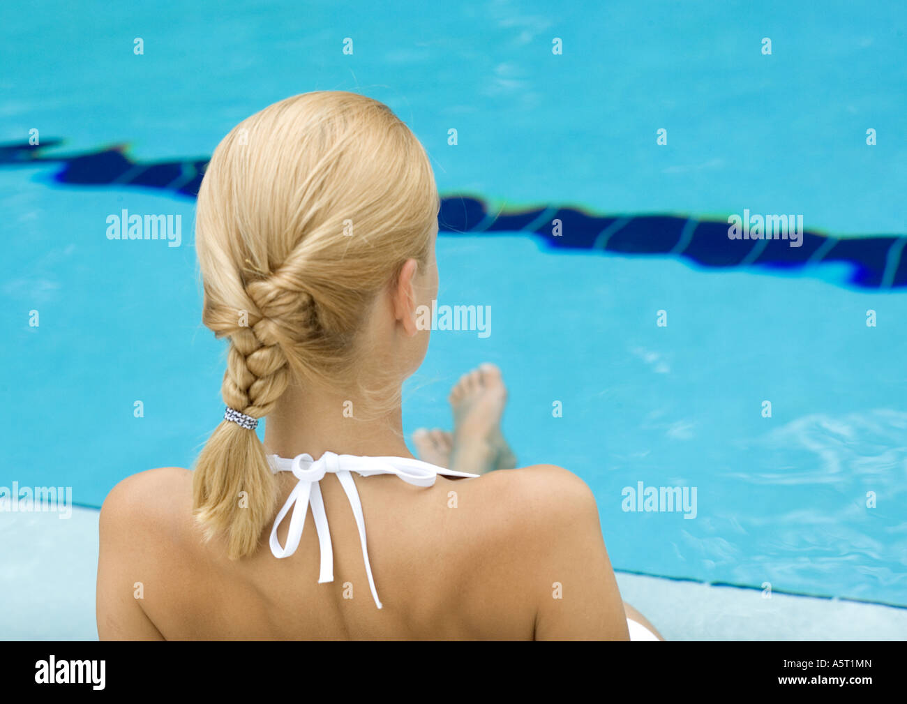 Young woman by edge of pool, feet in water, rear view Stock Photo - Alamy