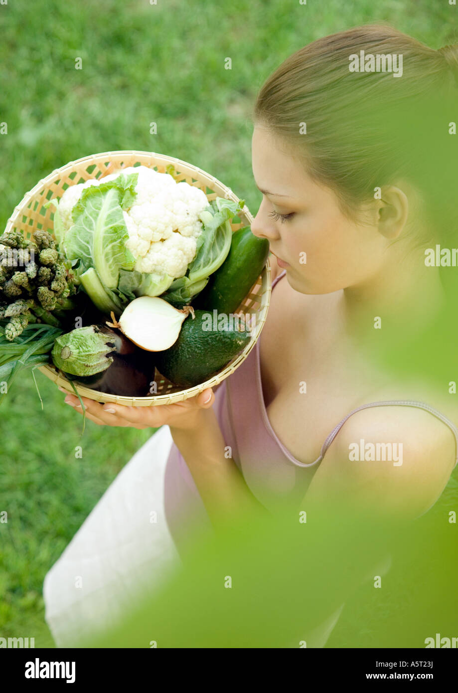 Woman holding basket full of fresh vegetables Stock Photo