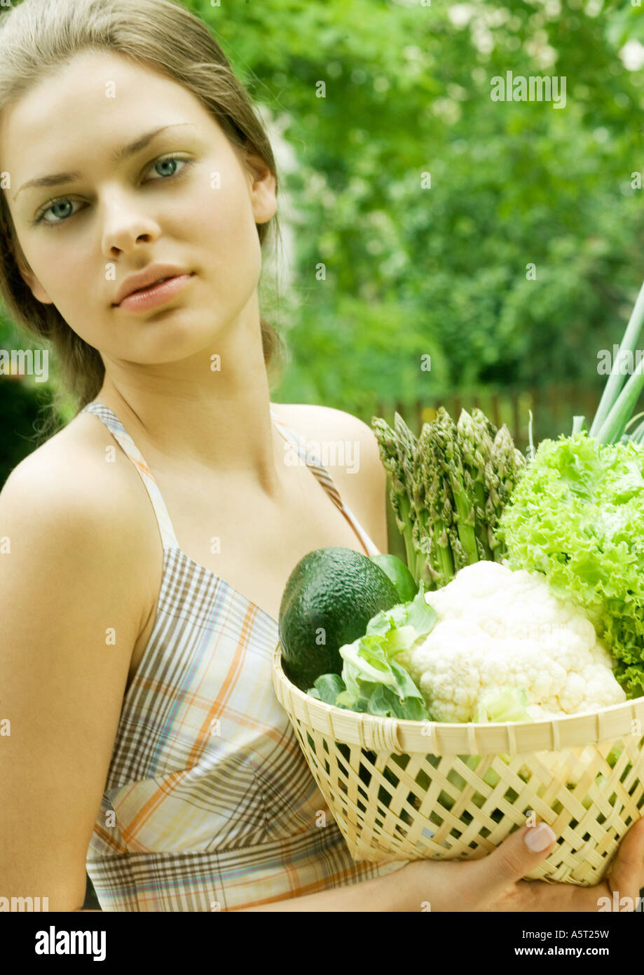 Woman holding basket full of fresh vegetables Stock Photo