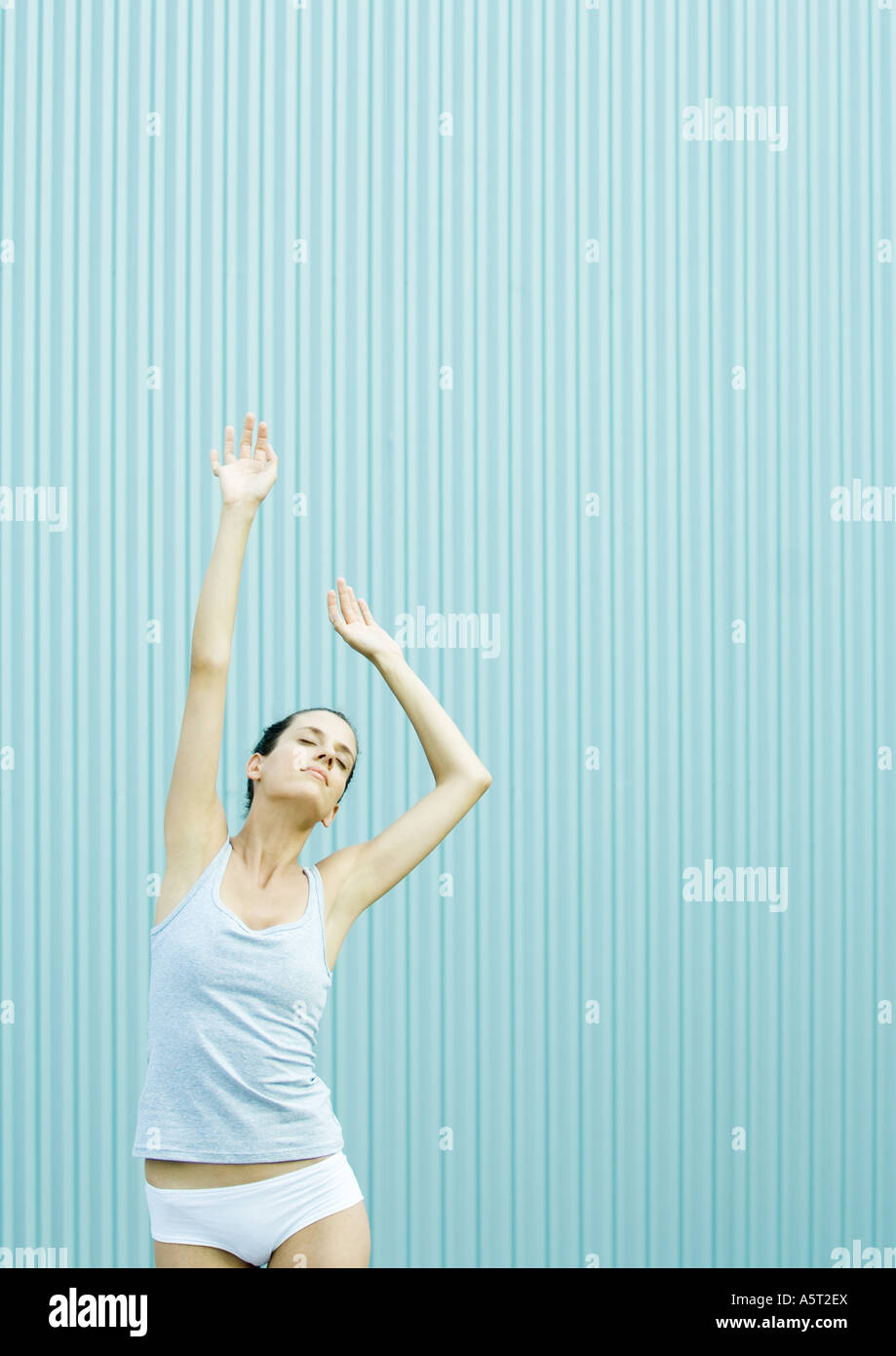Woman standing in underclothes, stretching Stock Photo