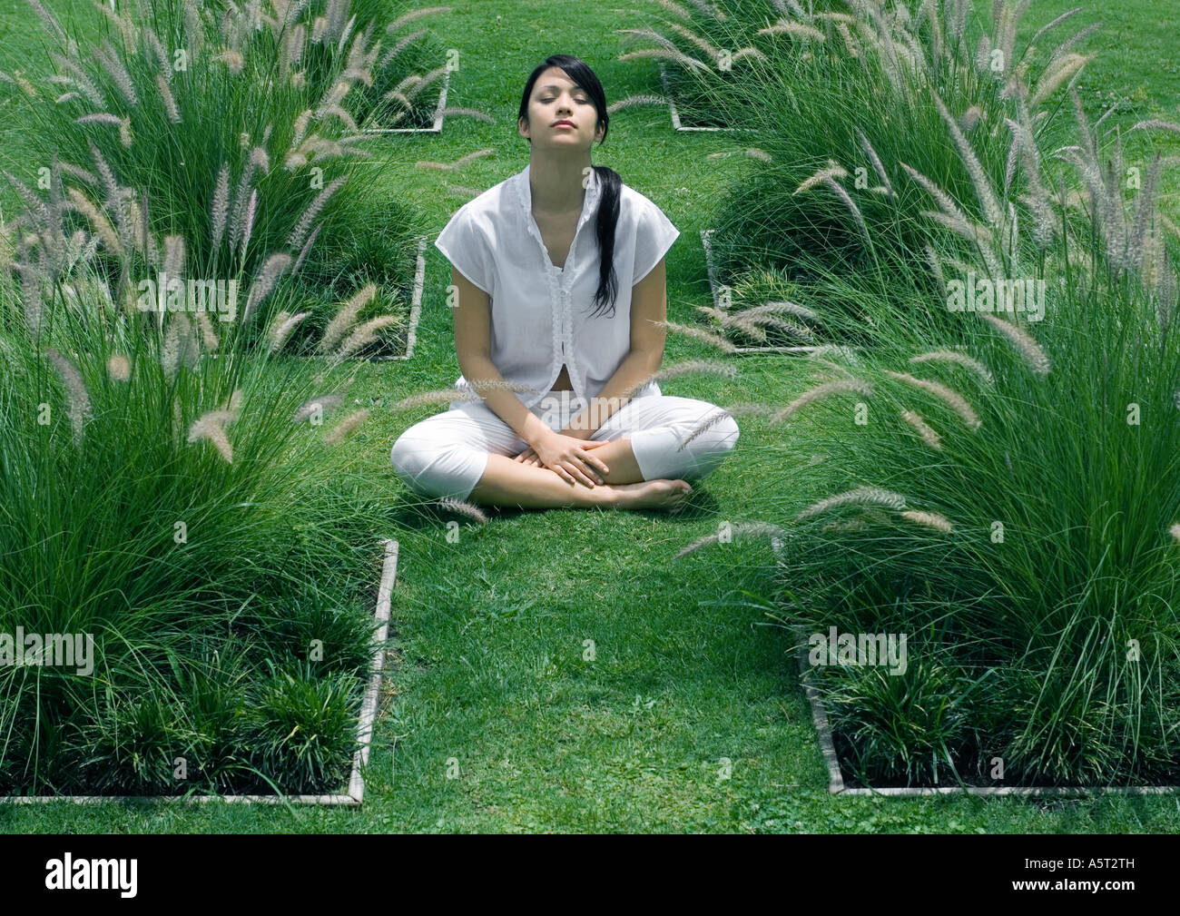 Woman sitting in ornamental garden with eyes closed Stock Photo