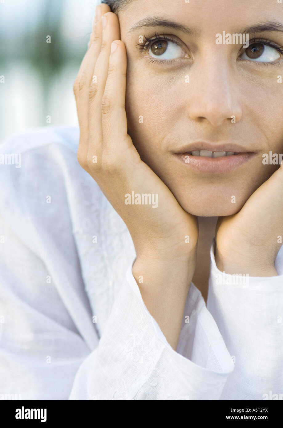 Woman resting head in hands, looking up Stock Photo