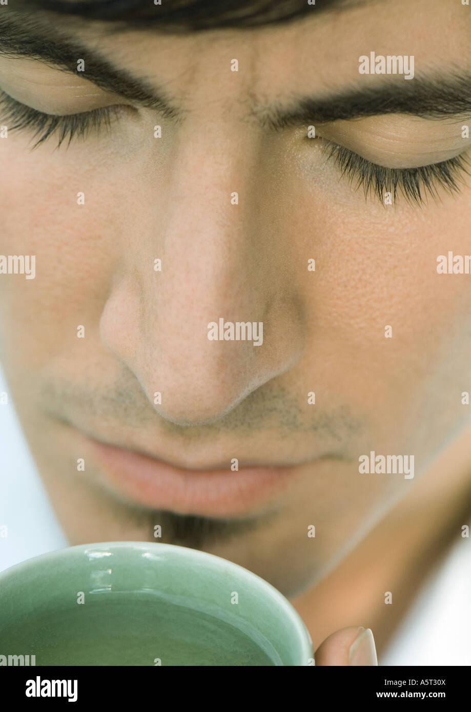 Man smelling cup of tea, eyes closed, close-up Stock Photo