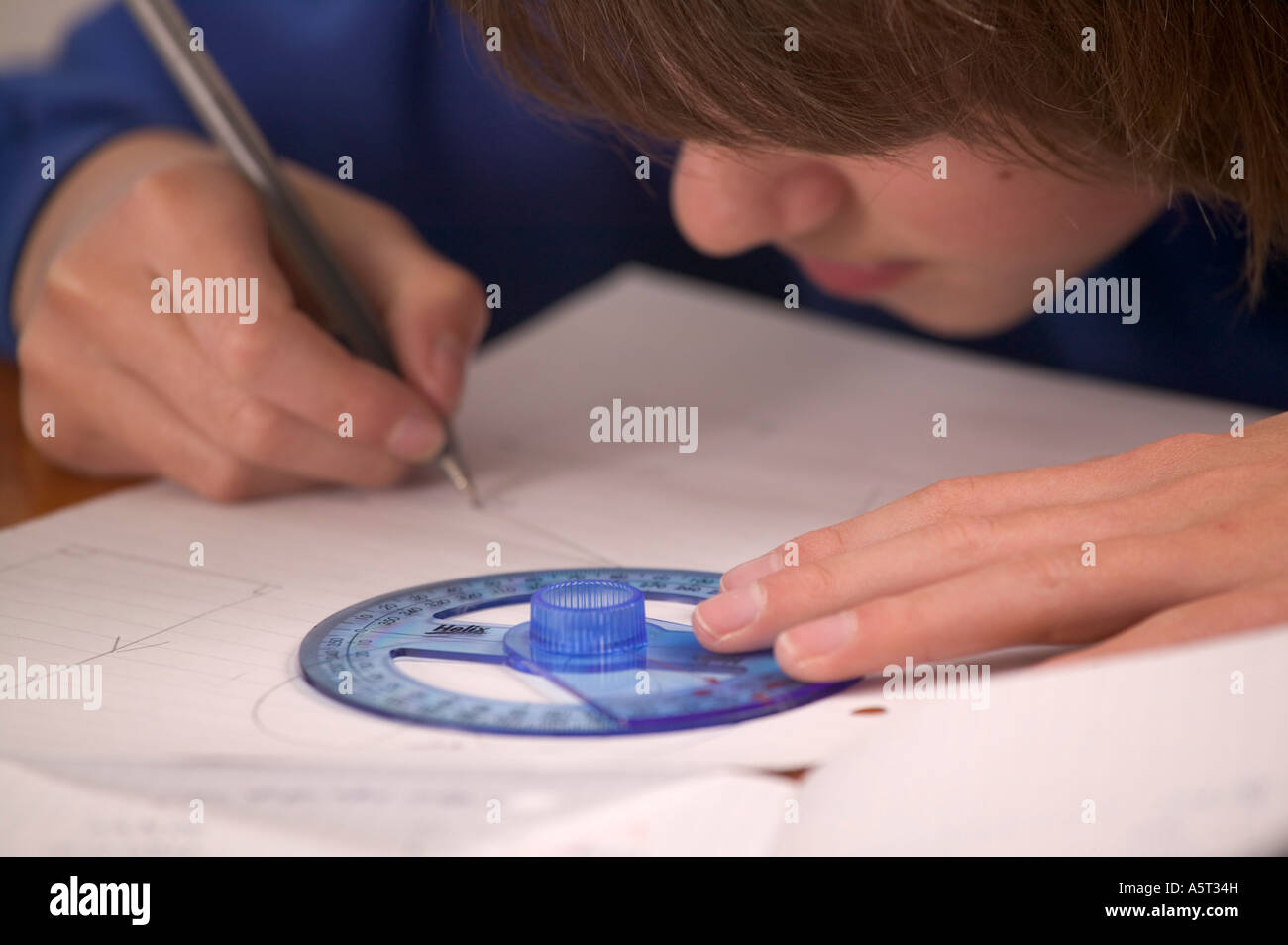 Young teen boy in school uniform doing maths work using a protractor Stock Photo