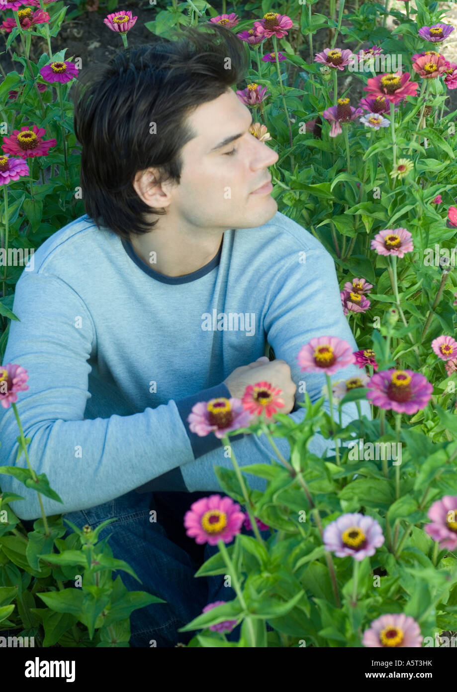 Man sitting in flowers, eyes closed Stock Photo