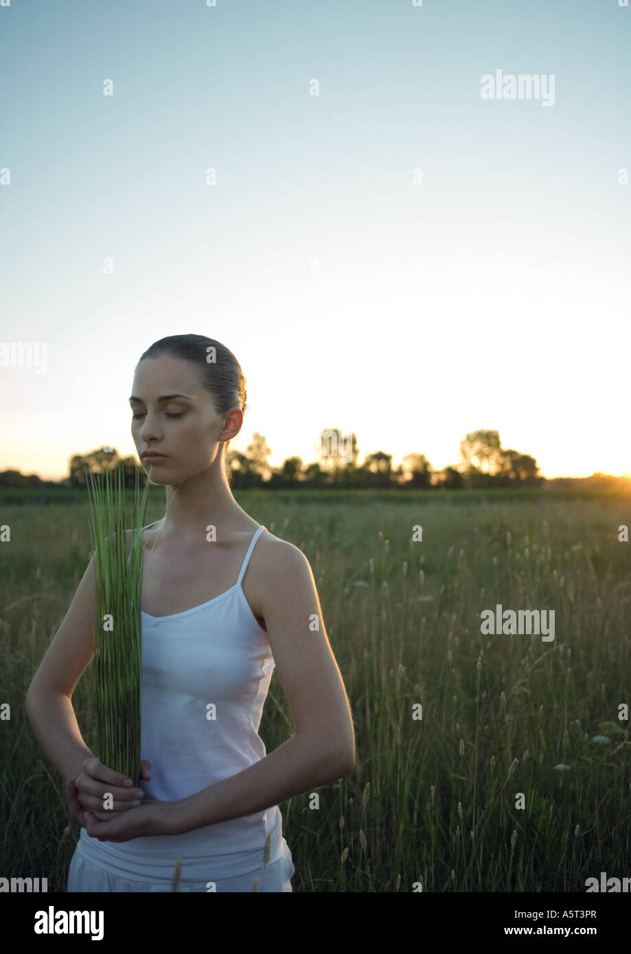 Woman standing, holding bundle of grass, eyes closed Stock Photo - Alamy