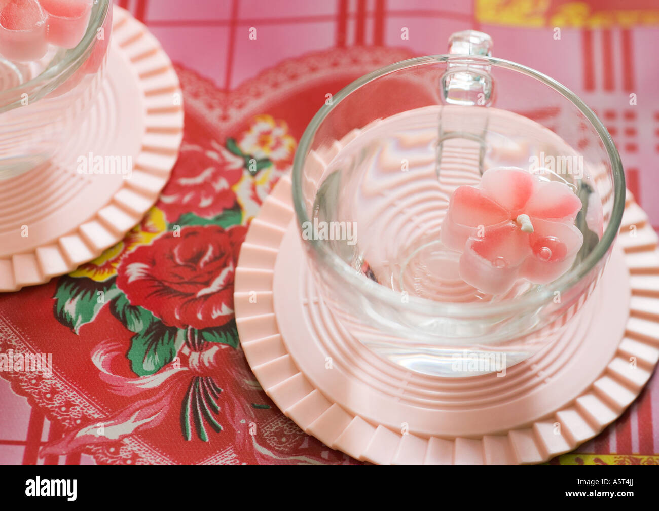 Flower-shaped candle floating in cup Stock Photo