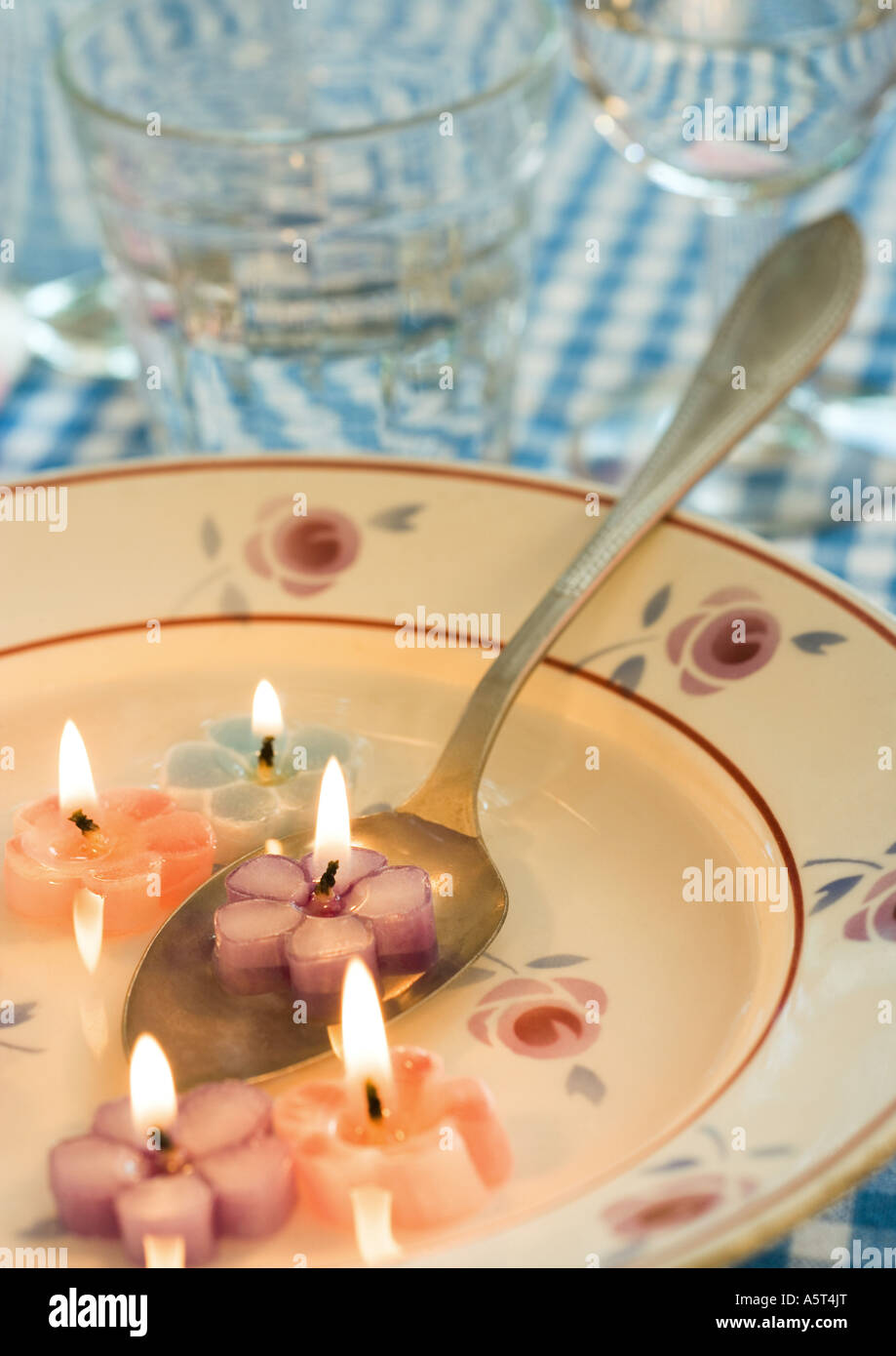 Lit flowershaped candles in soup plate, with spoon Stock Photo Alamy