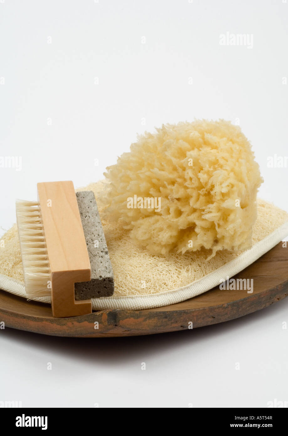 Pumice stone, brush, loofah, and natural sponge on wooden tray Stock