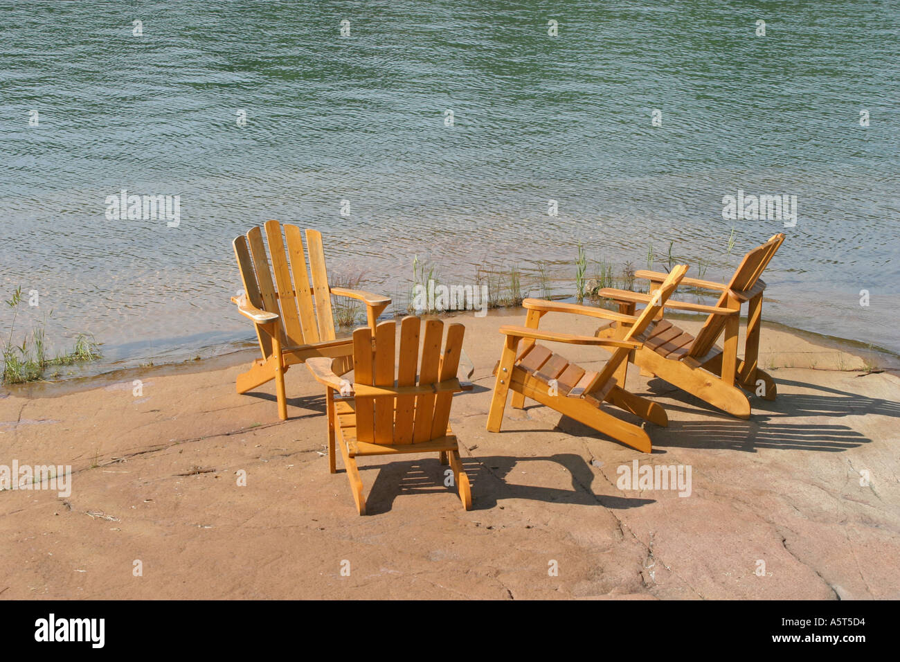 Four Deck Chairs On Rock Platform By Lake Stock Photo