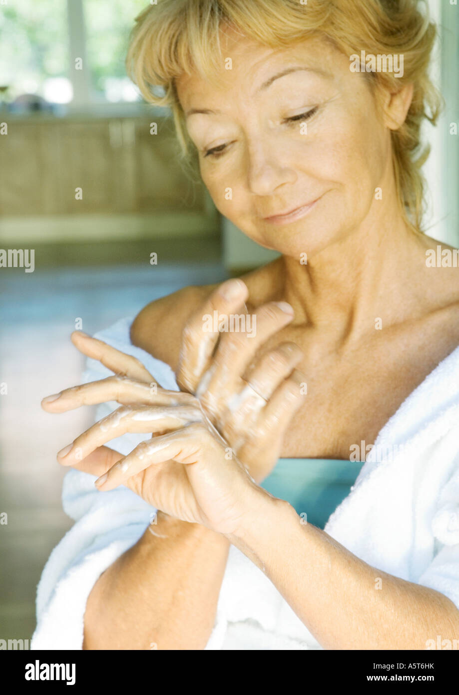 Senior woman applying moisturizer to hands Stock Photo