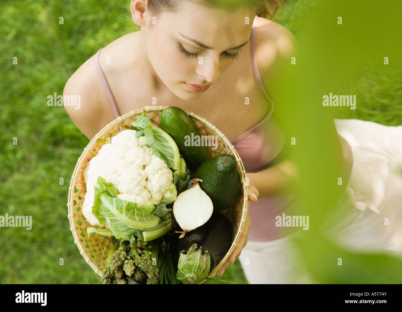 Young woman holding up basket full of vegetables Stock Photo - Alamy