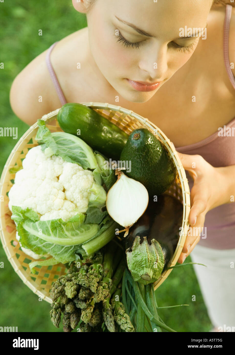 Young woman holding up basket full of vegetables Stock Photo - Alamy