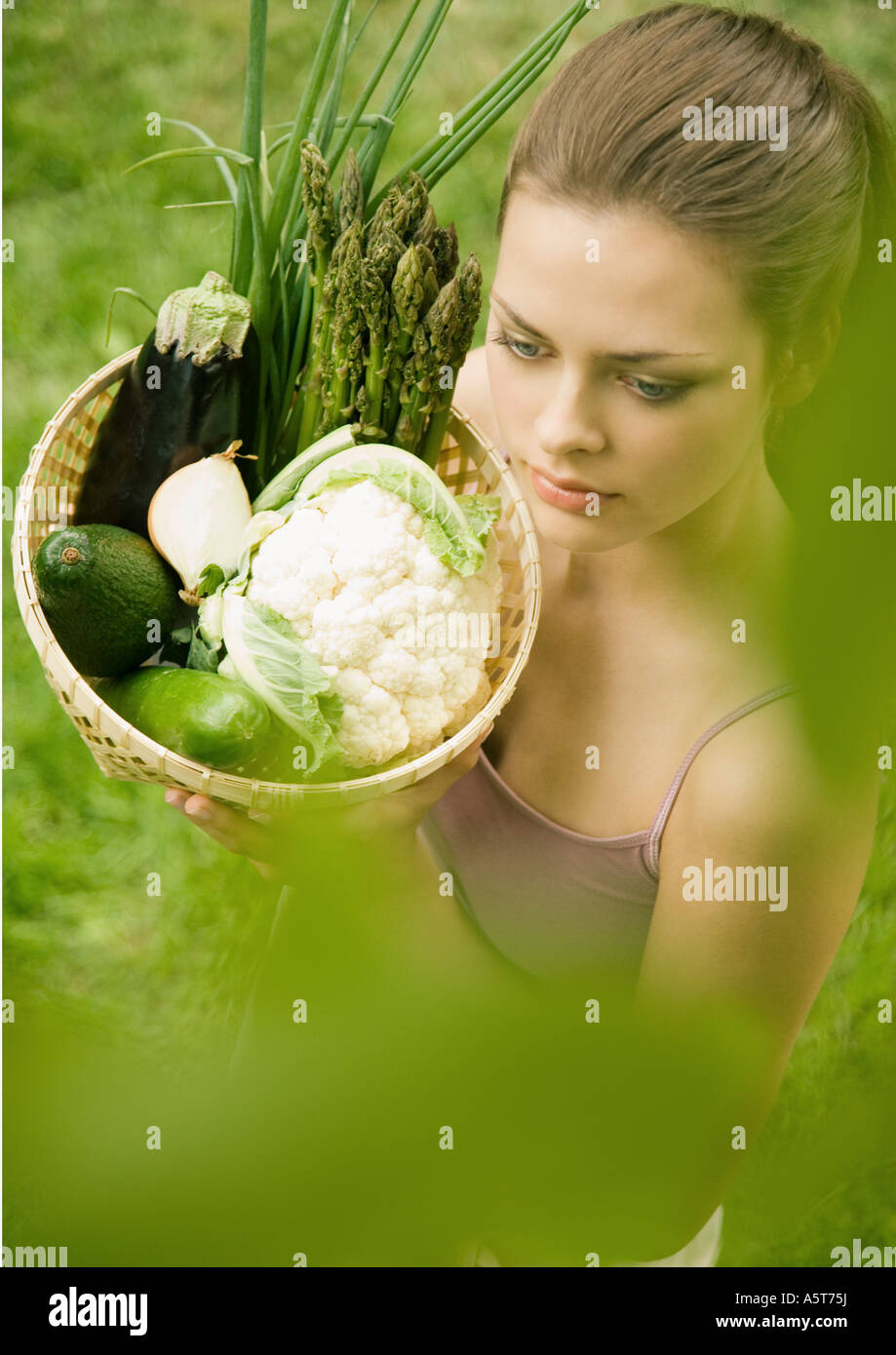 Young woman holding up basket full of vegetables Stock Photo - Alamy