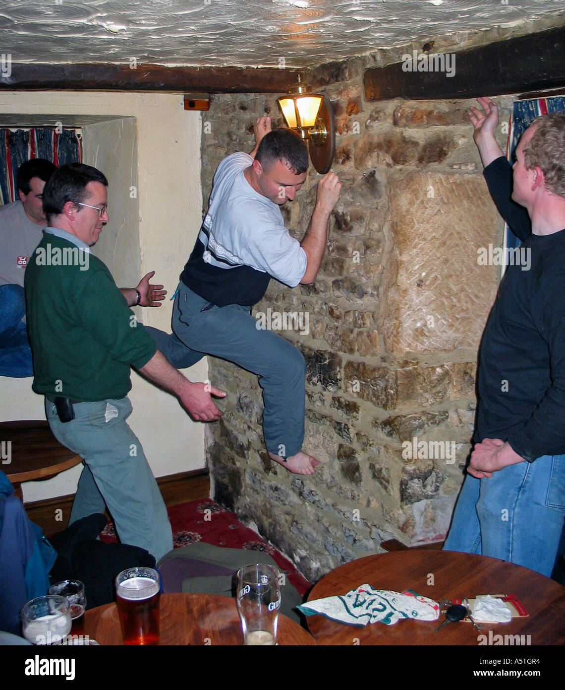 Young men indoor climbing the walls in an Inn after a few beers during a stag party weekend Stock Photo