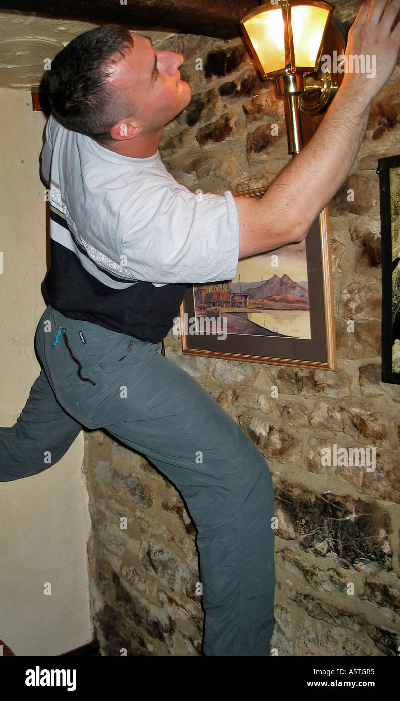 Young man indoor climbing the walls in an Inn after a few beers during a stag party weekend Stock Photo
