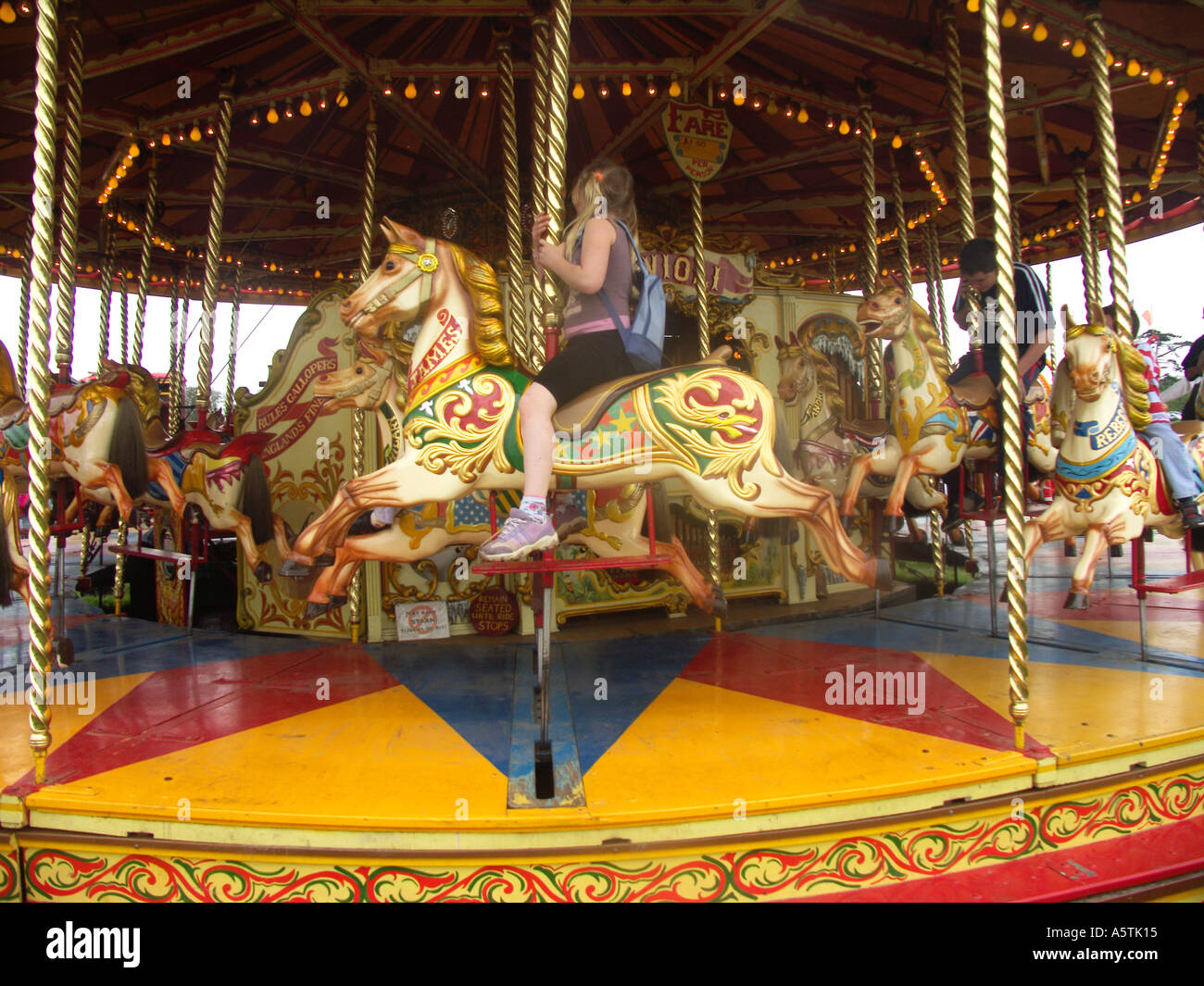 Children riding old fashioned roundabout horse carousel merry go round Stock Photo