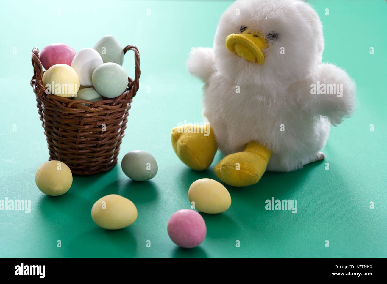 Easter eggs basket with colorful marzipan sweets on green background with toy duck Stock Photo