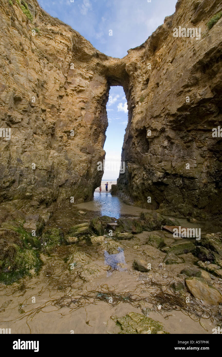Young children exploring the rock pools underneath natural archway,  Perranporth, Cornwall UK Stock Photo