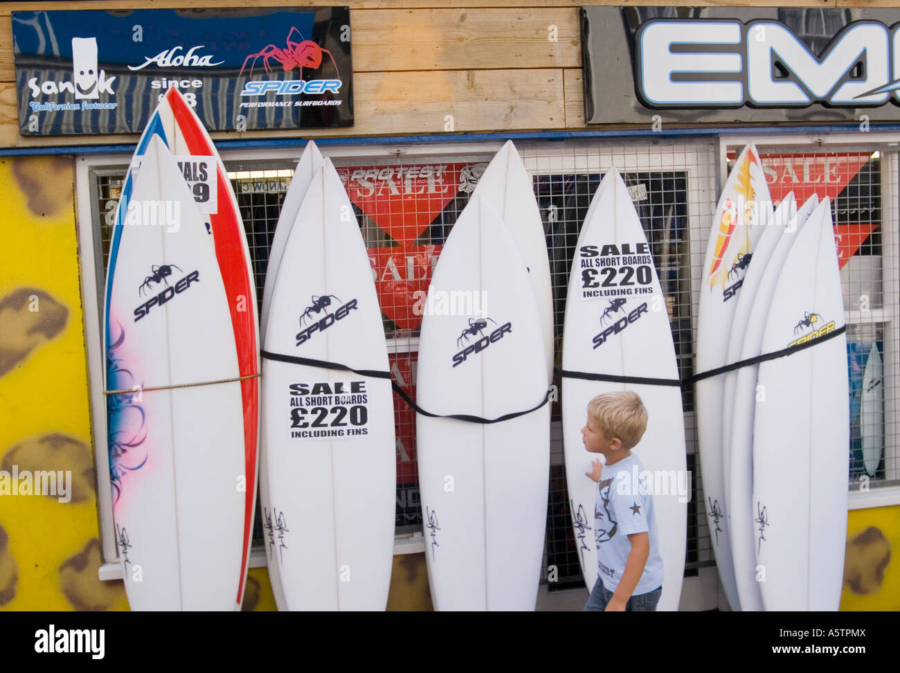 Young boy looks at surfboards outside shop, Newquay, Cornwall UK Stock Photo