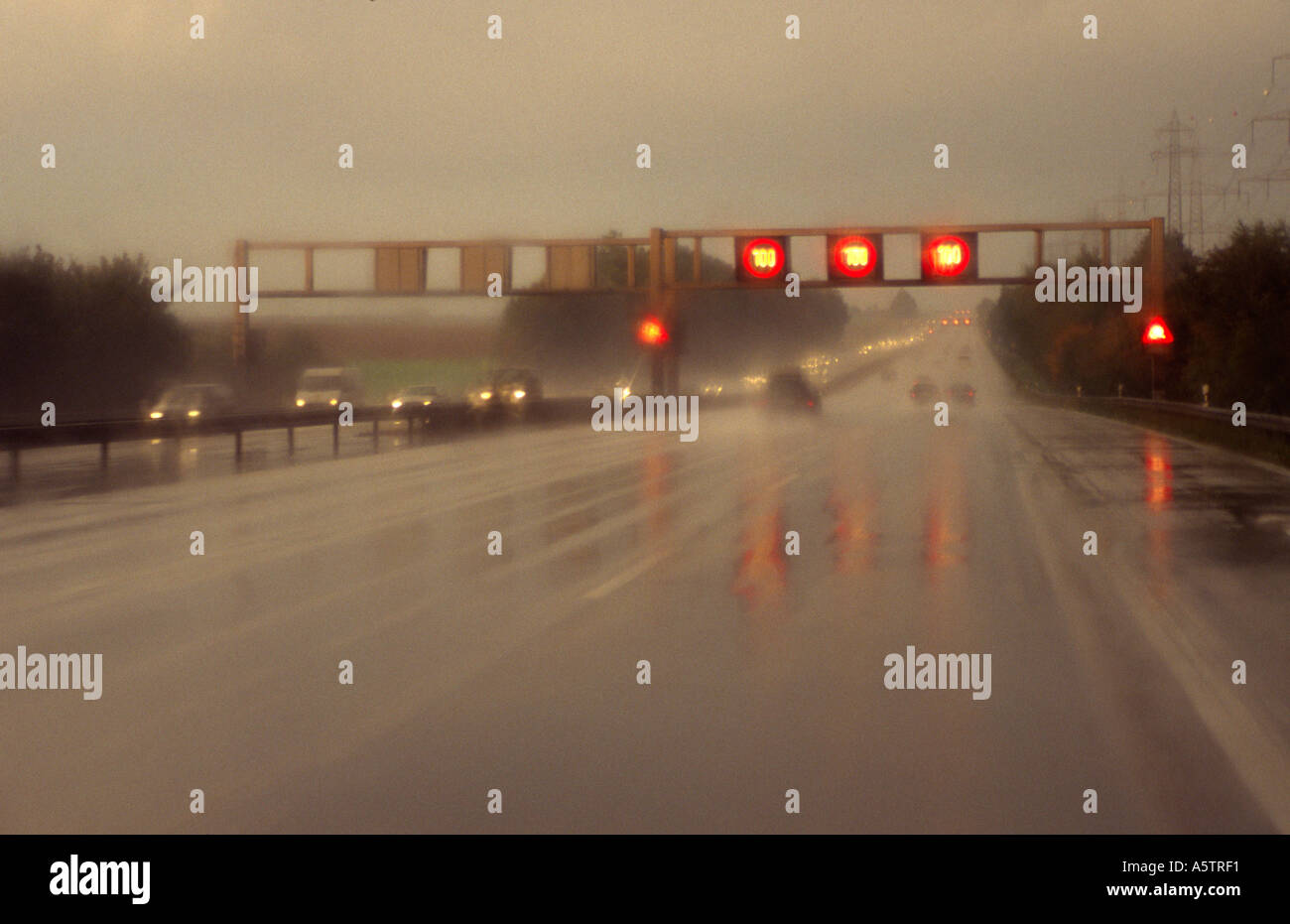 electric signs for speed limit above a moroway with bad sight on rainy weather Stock Photo