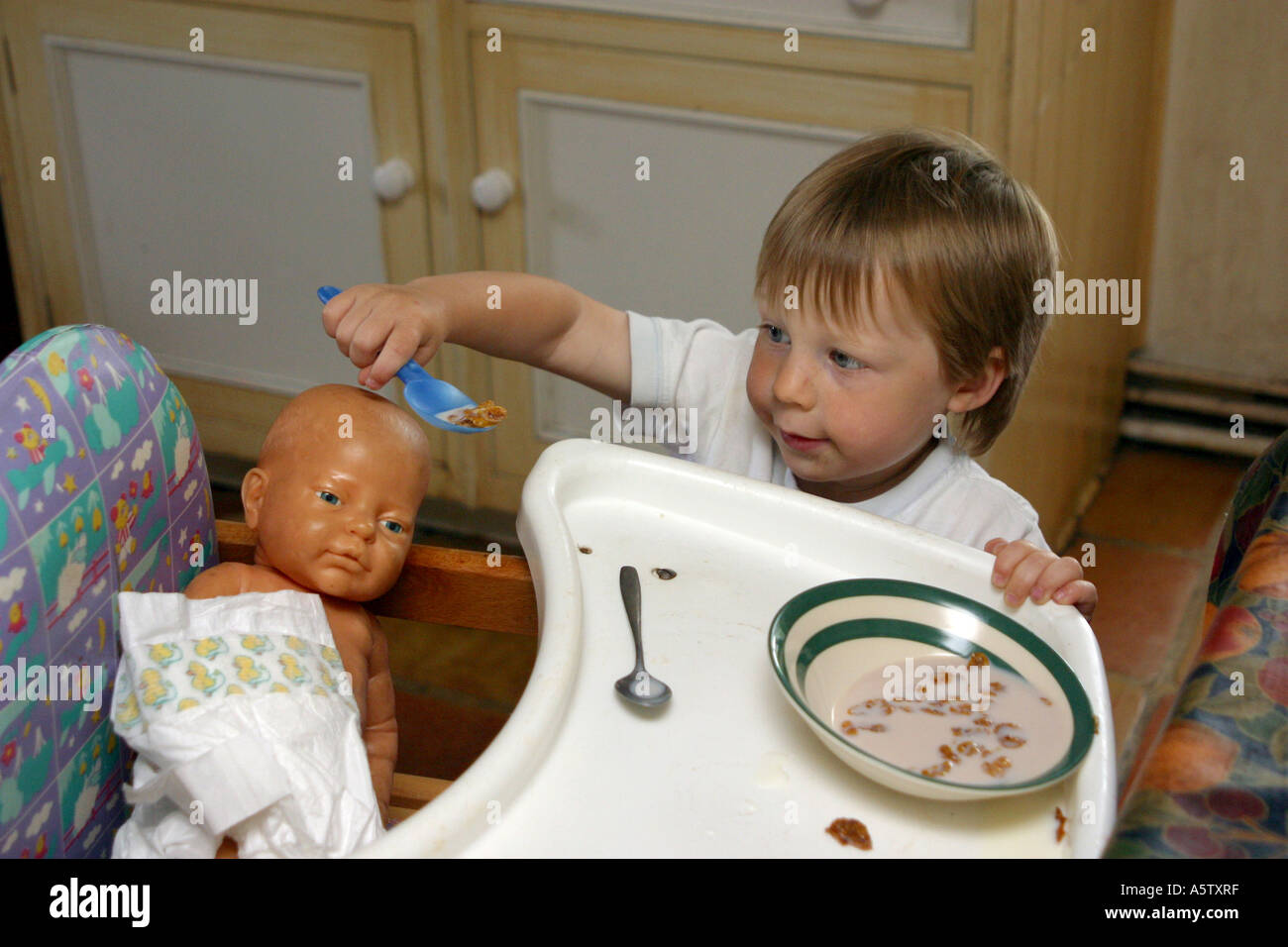 three year old boy play feeding his toy doll Stock Photo