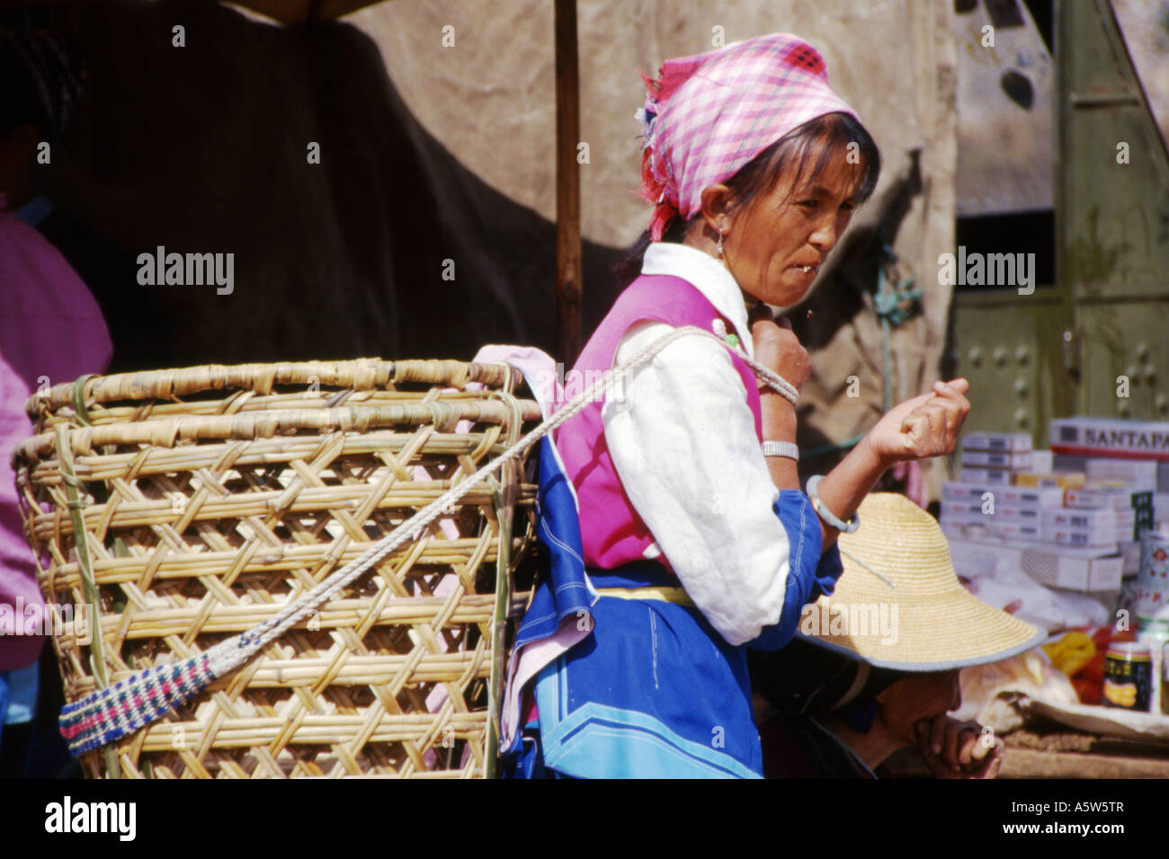 Naxi woman in traditional dress,large wicker basket on her back,Wase market near Dali,Yunnan province,China. Stock Photo