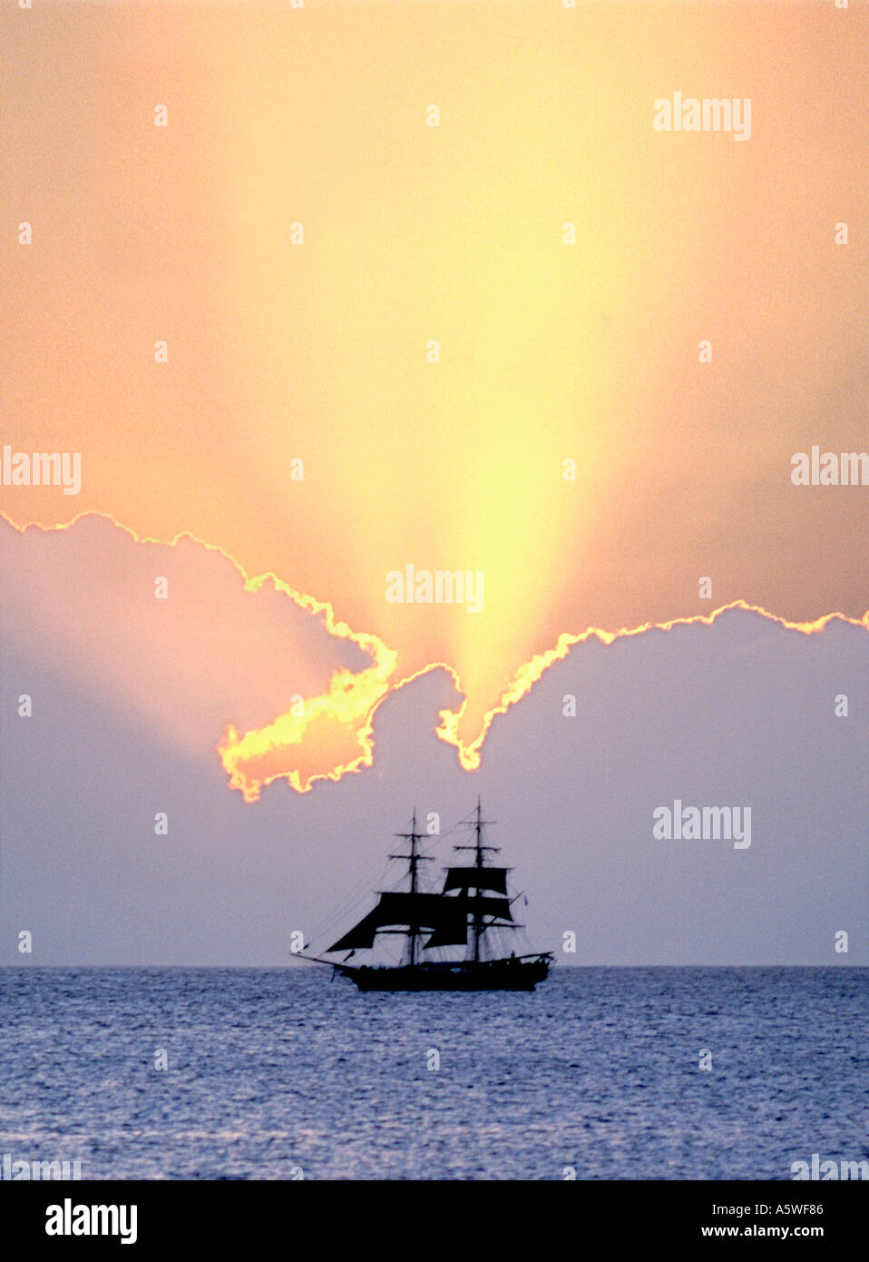 A boat silhouetted against the sunset in the Caribbean. Stock Photo