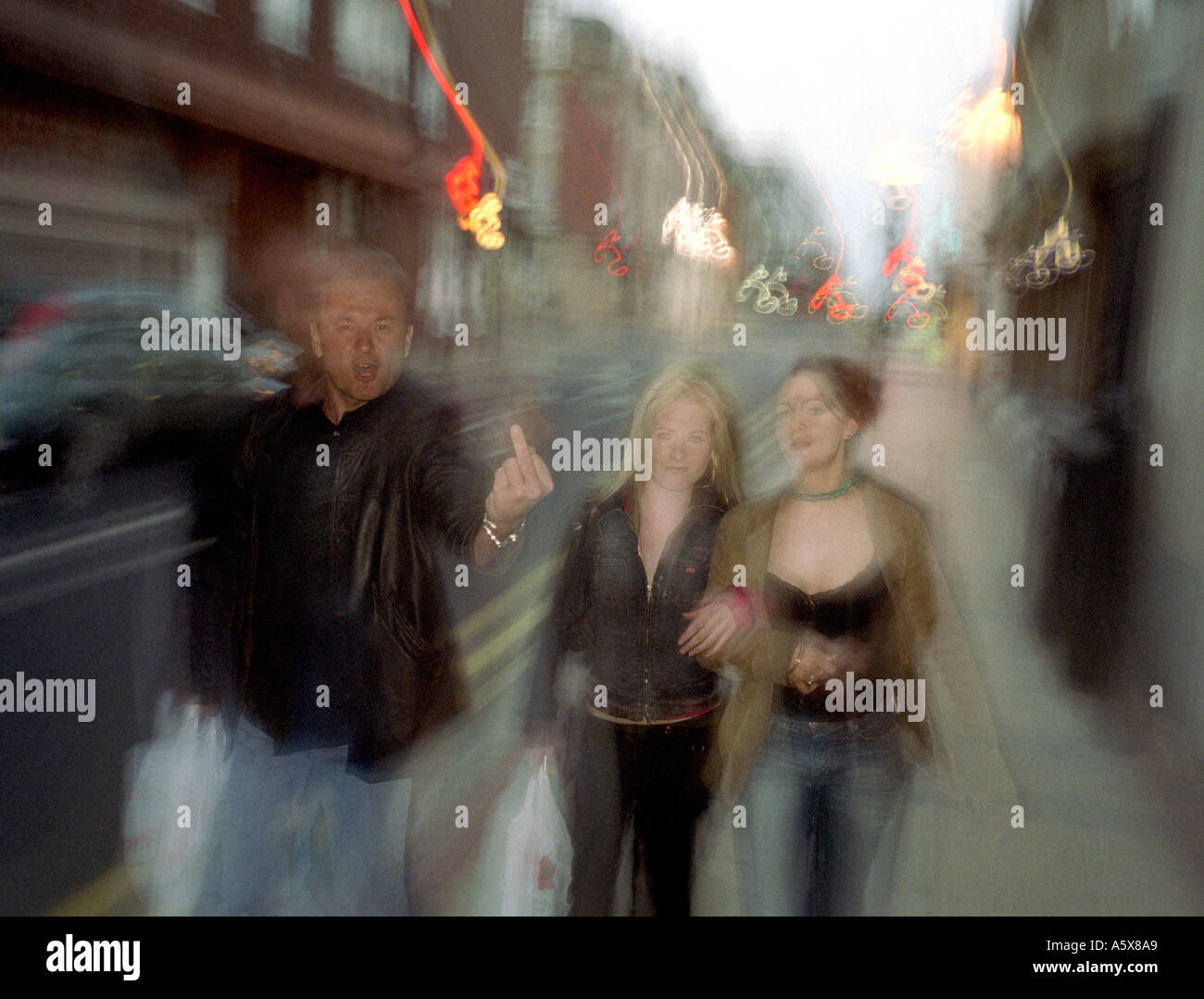 a man walking with two young women makes a gesture Stock Photo - Alamy