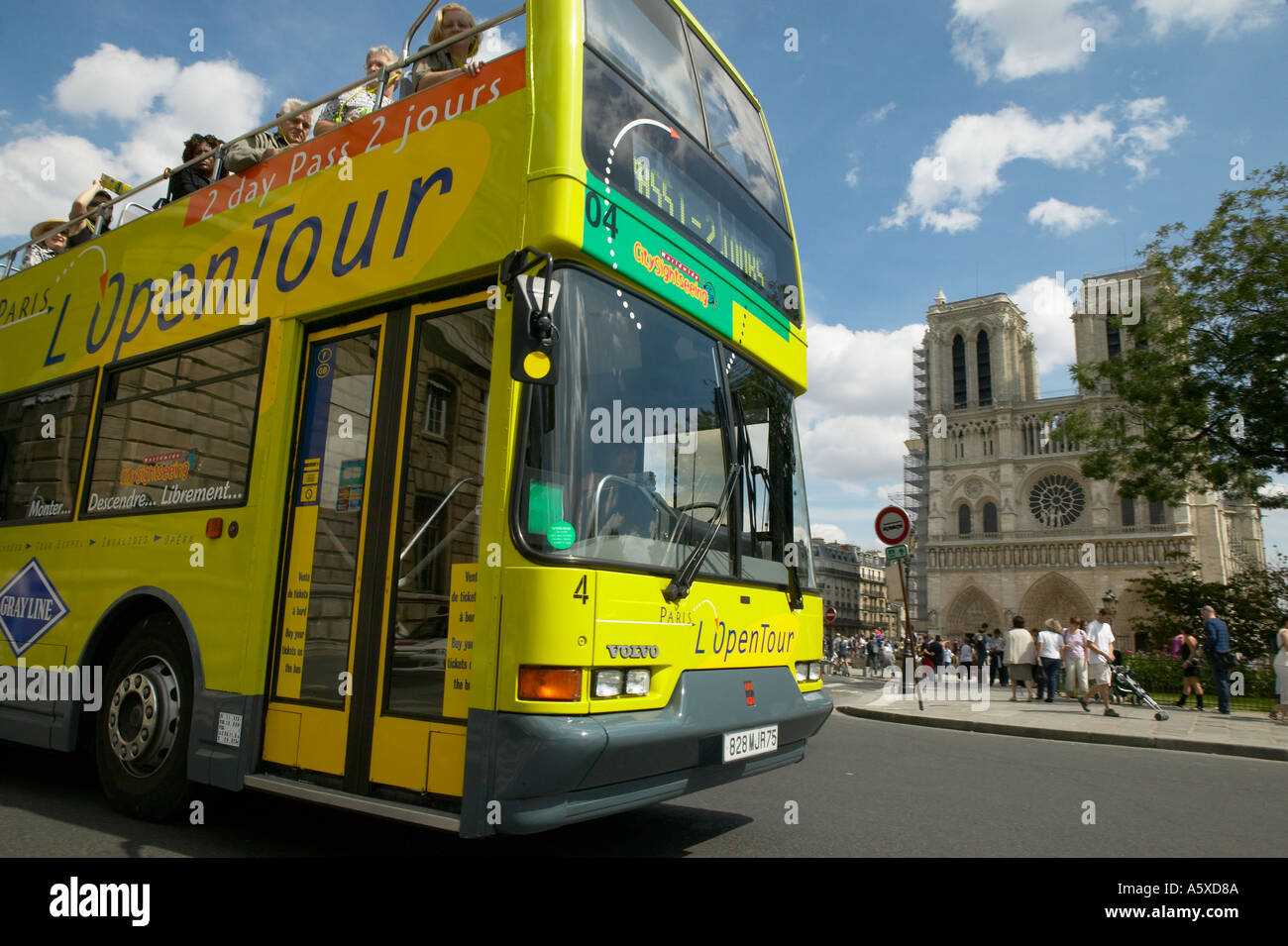 Yellow double decker bus taking tourists past Notre Dame cathedral in
