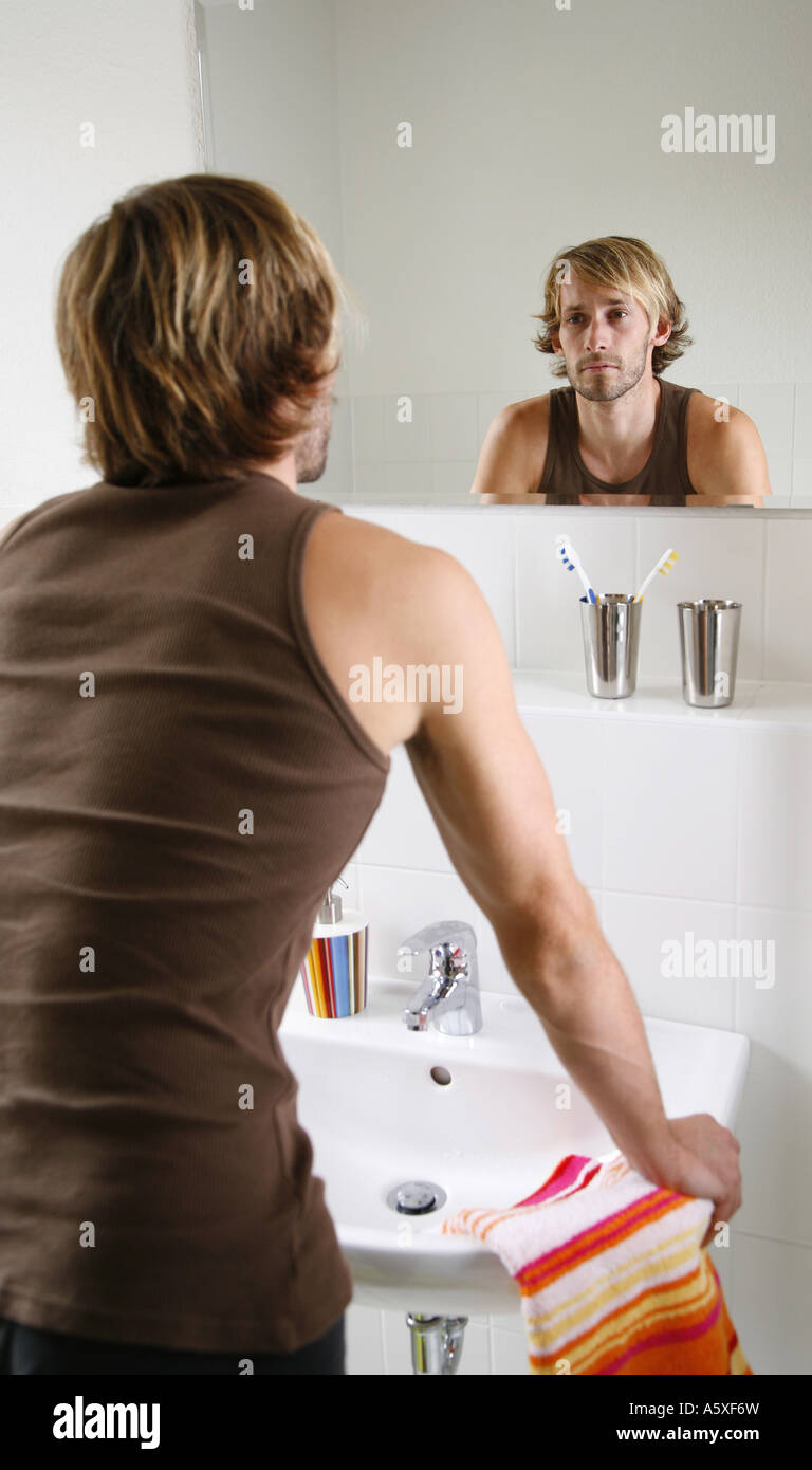 Young man looking in mirror in bathroom close up Stock Photo