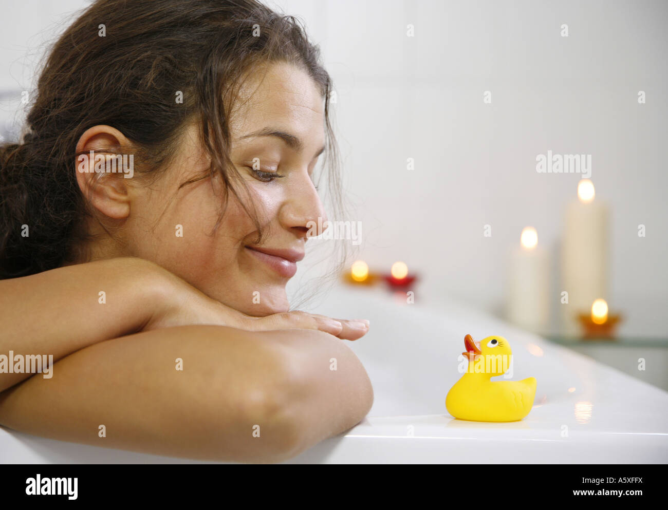 Young woman leaning on bath tub and looking at rubber duck close up portrait Stock Photo