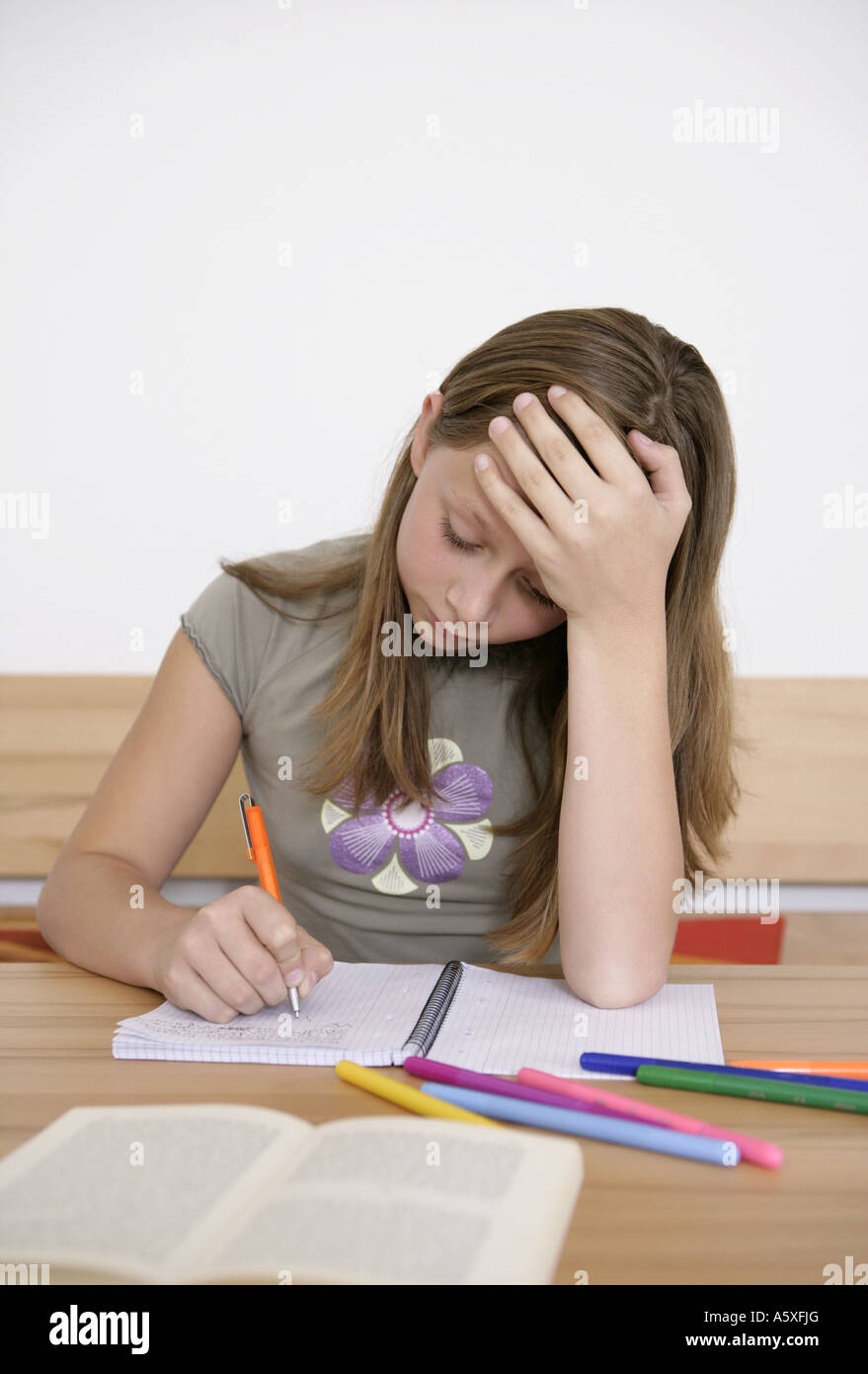 Girl with pen and exercise book on desk Stock Photo