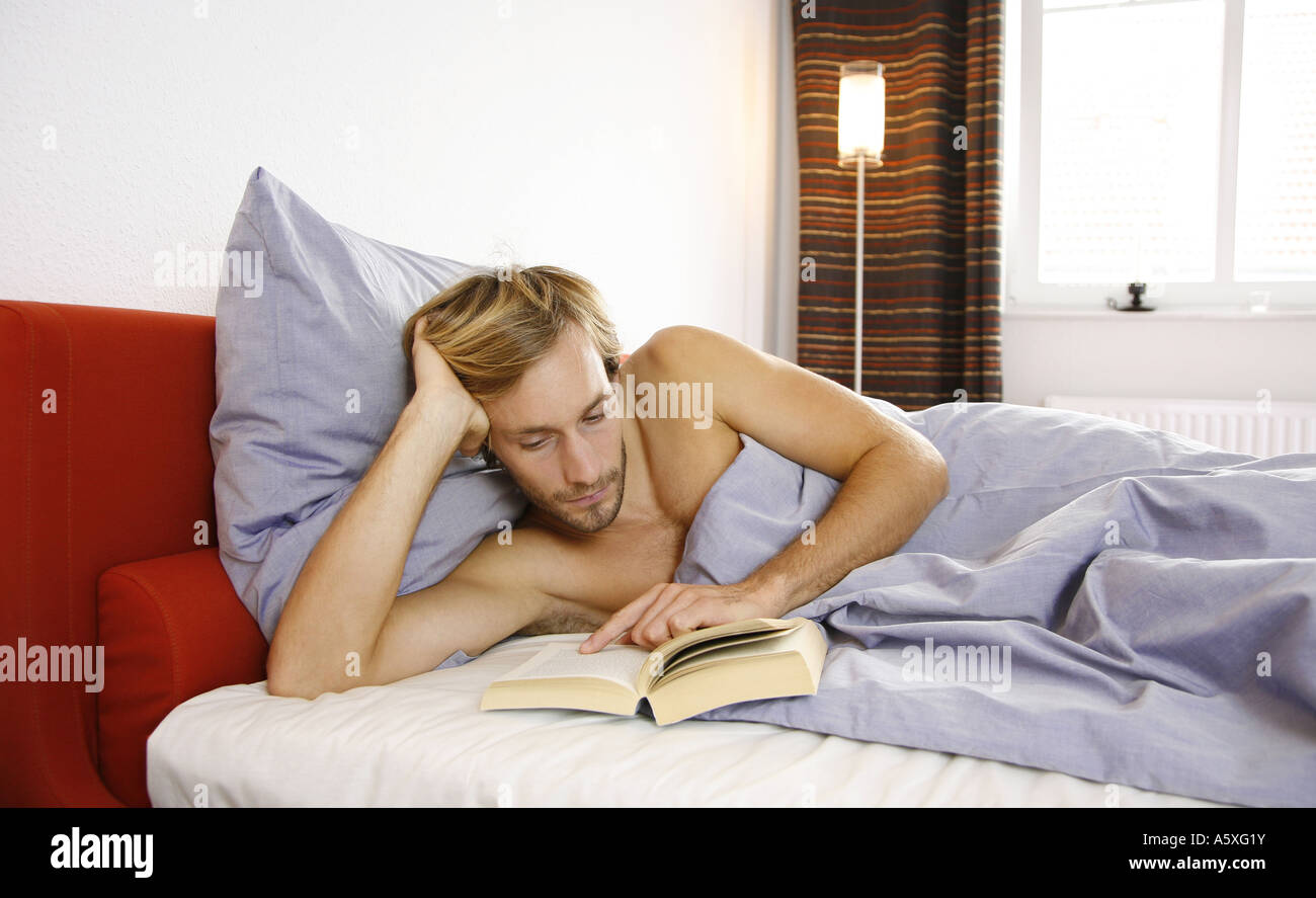 Young man reading book on bed Stock Photo