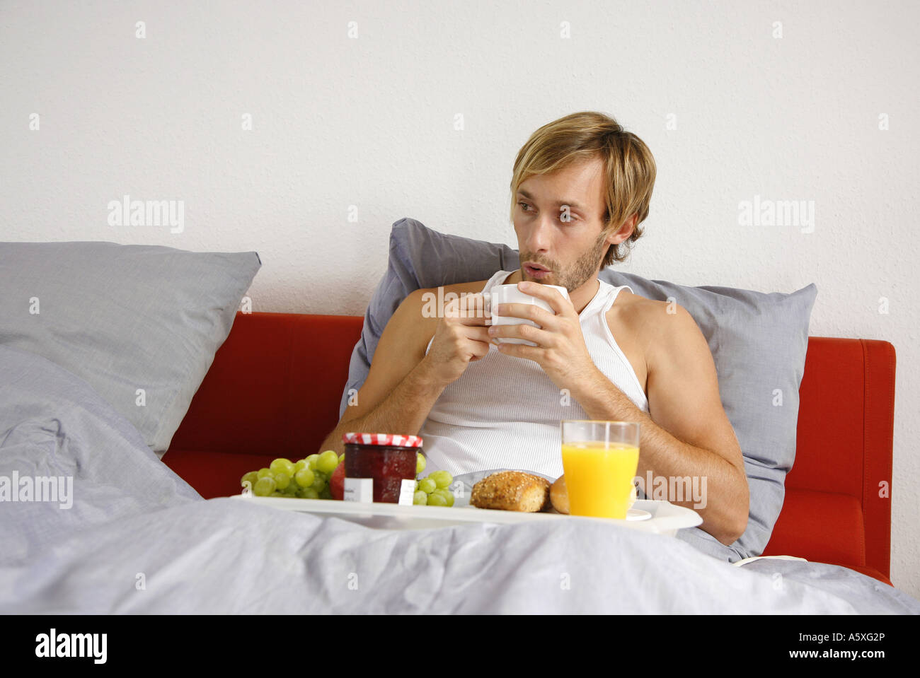 Young man having breakfast on bed portrait Stock Photo