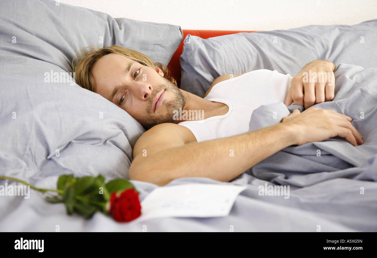 Young man looking at love letter lying on bed Stock Photo