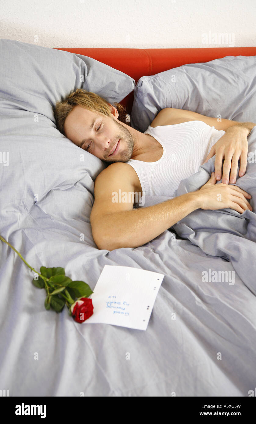 Young man looking at love letter lying on bed smiling high angle view Stock Photo