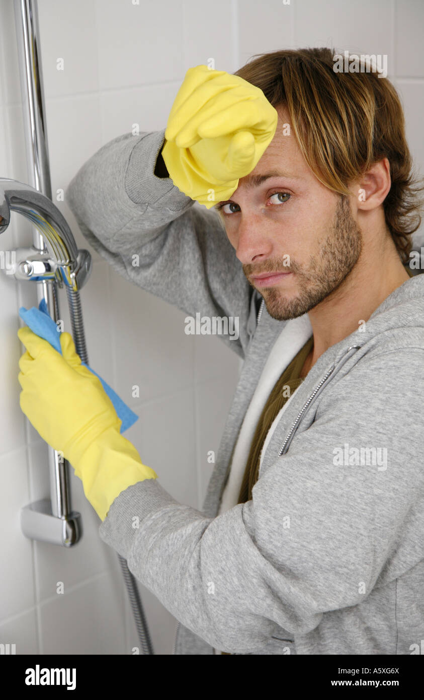 Young man cleaning shower rubbing forehead Stock Photo