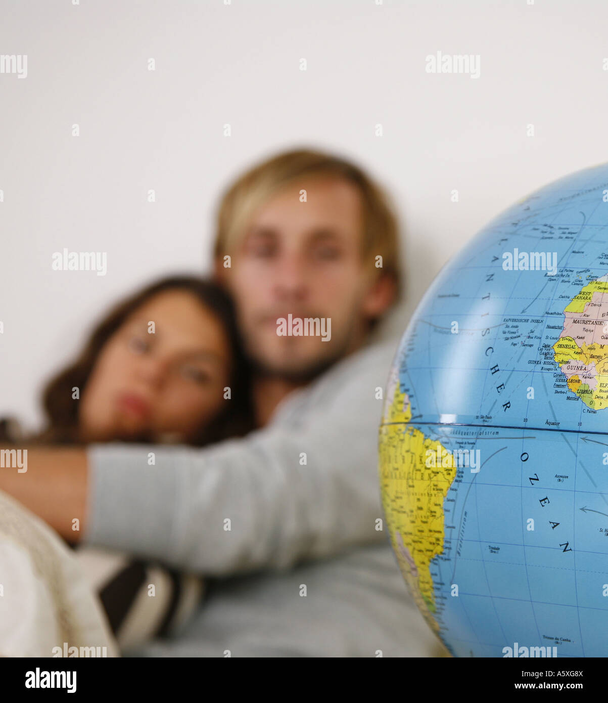 Young couple on couch looking at globe focus on globe Stock Photo